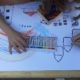 Kinder malen eine Stadt mit Häusern, Wolken und Regenbogen. Auf dem Bild steht "Happi" - gemeint ist das englische "happy" = glücklich