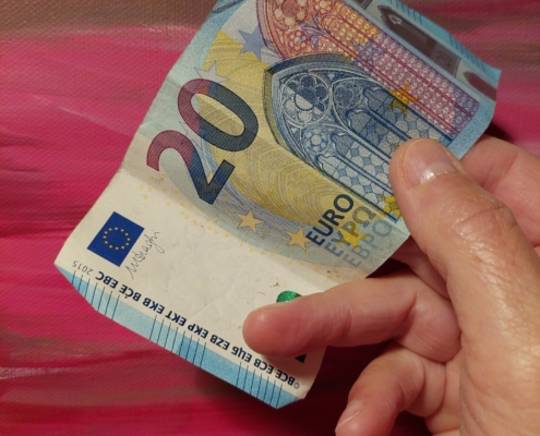 Hand reicht einen 20 Euro-Schein