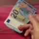 Hand reicht einen 20 Euro-Schein