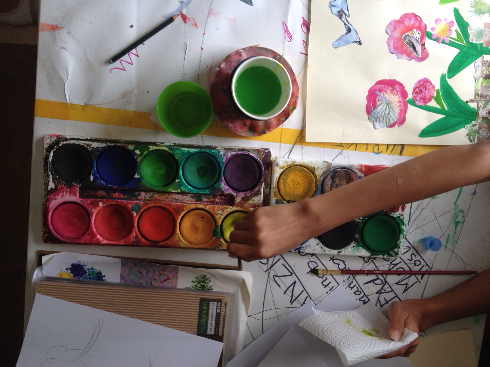 Malkasten mit Pinsel - ein Kind ist kreativ mit Farbe und Kleben.