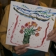 alte Frauenhände halten ein Bild mit Blumen in einer Vase hoch